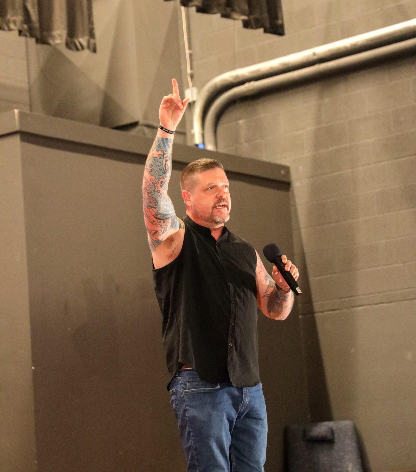 Steve Baumgartner on stage, arm raised, microphone in hand